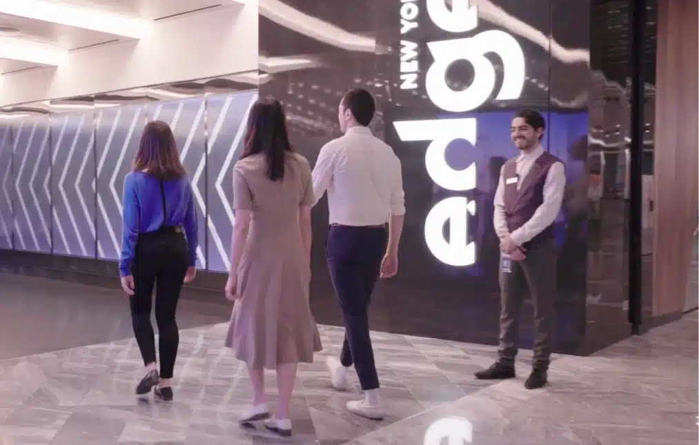 Guests walking into Edge’s entrance, welcomed by a smiling staff member in uniform