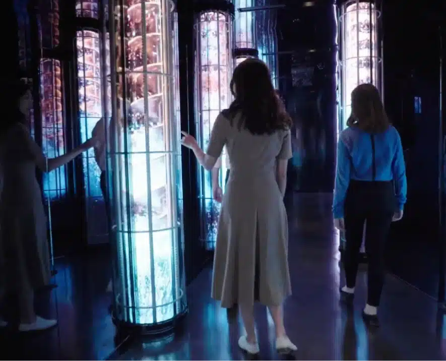Visitors engaging with illuminated vertical displays in a dark, reflective immersive exhibit