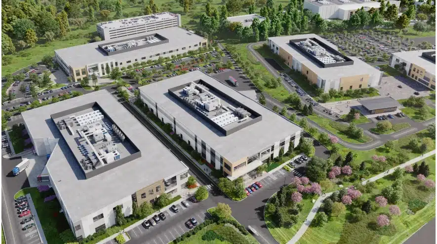 Aerial view of a modern industrial complex surrounded by greenery and parking areas