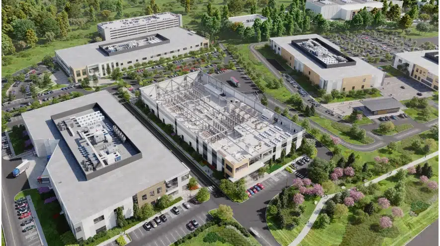 Aerial rendering of a biotech campus with modern facilities, parking lots, and landscaped green spaces