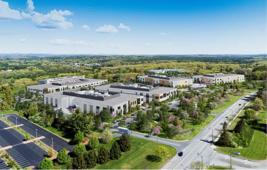 Aerial view of a biotech campus with multiple office buildings, parking spaces, and green landscaping