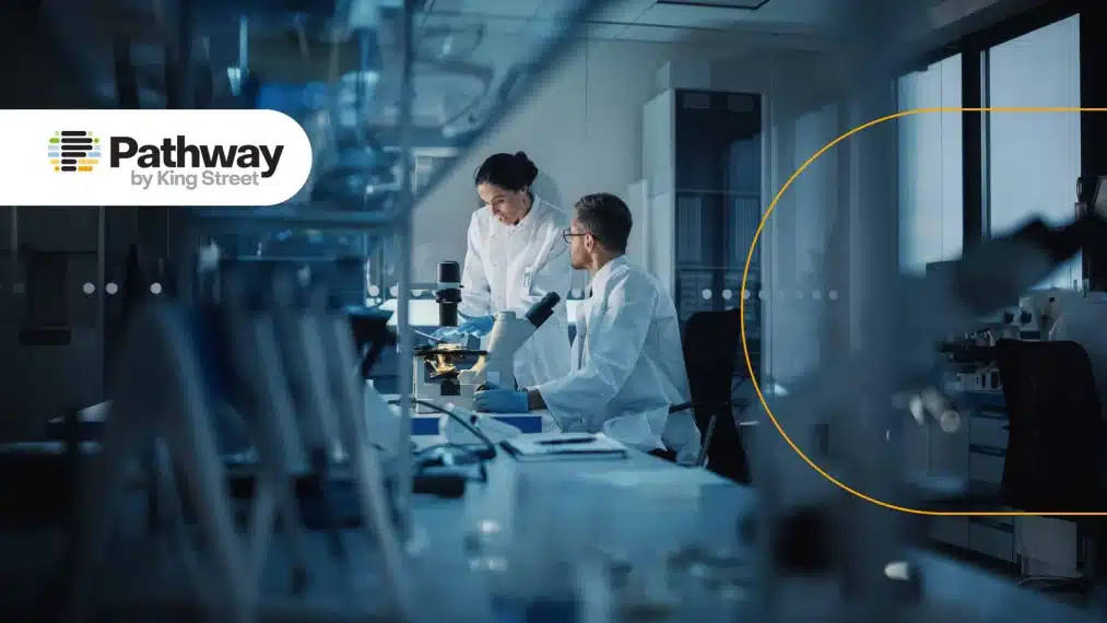 Scientists working in a biotech laboratory under blue lighting, with the Pathway logo in the corner