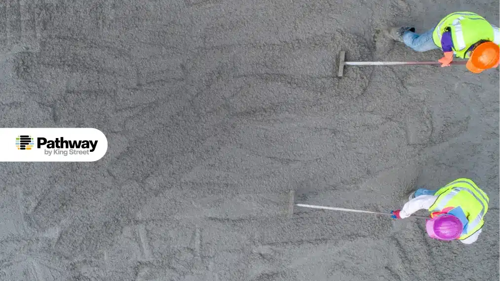 Construction workers in safety gear smoothing concrete foundation for a biotech facility project