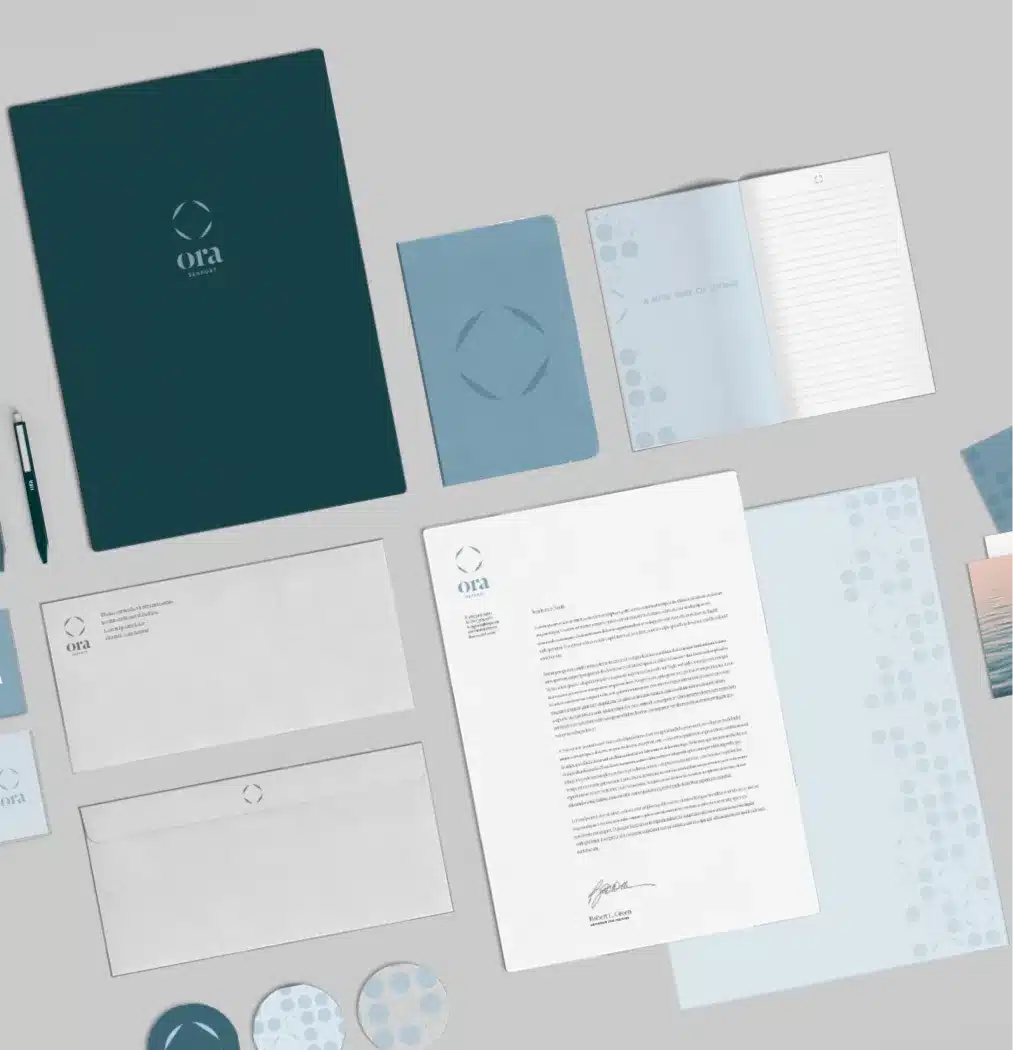 Collection of Ora Seaport branded stationery including notebooks, envelopes, and business materials