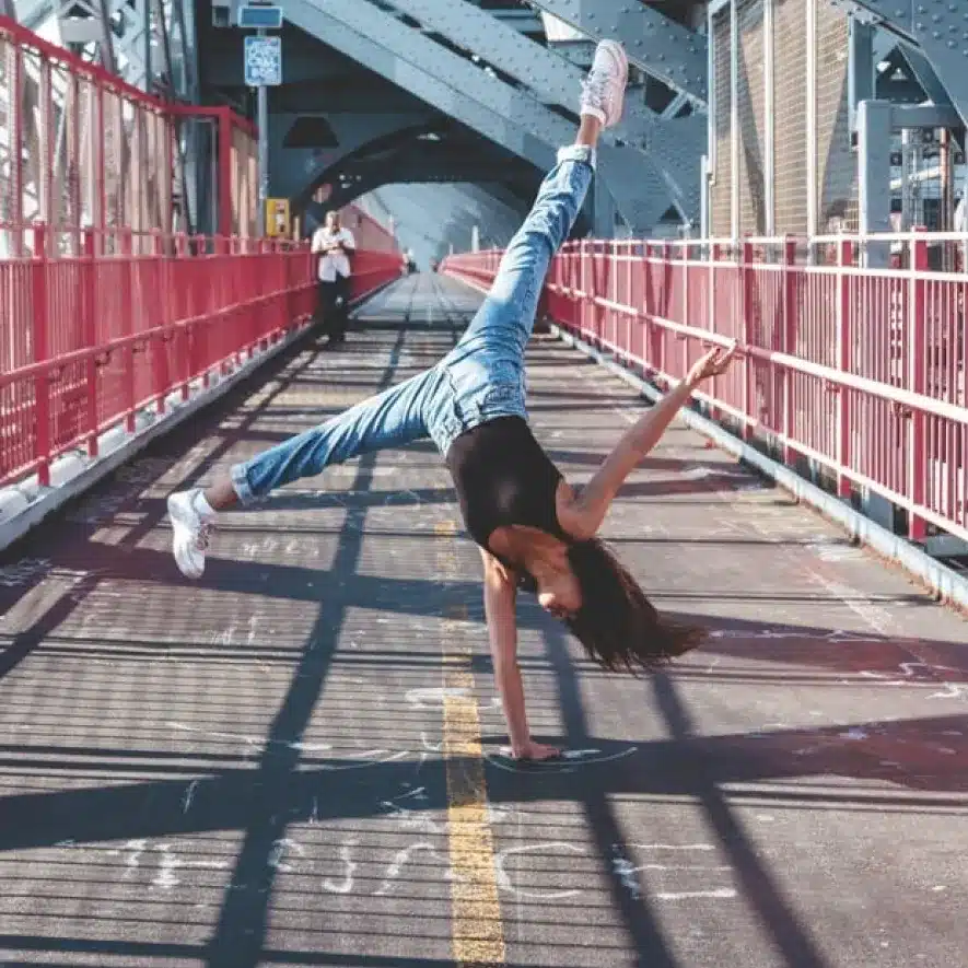 Young woman performing a cartwheel on a Williamsburg bridge, exuding energy and movement