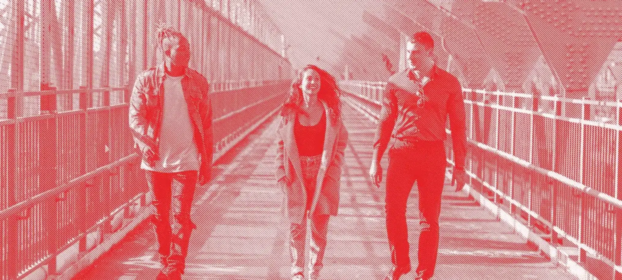 Solarized red-tone photo of three people walking across a bridge, embodying urban vibrancy