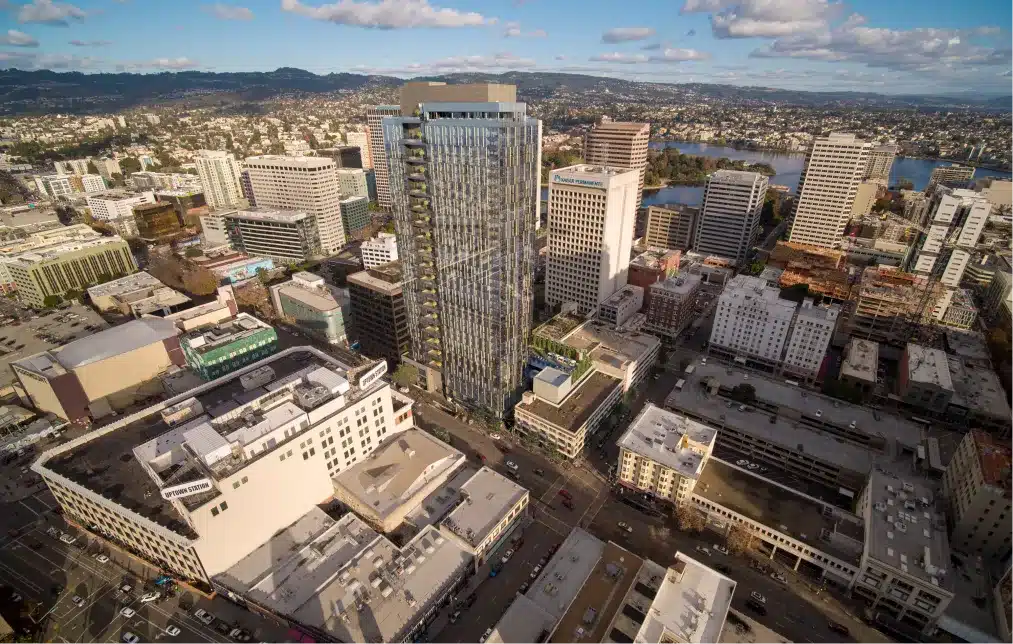 Aerial view of a glass high-rise skyscraper surrounded by city buildings and urban streets