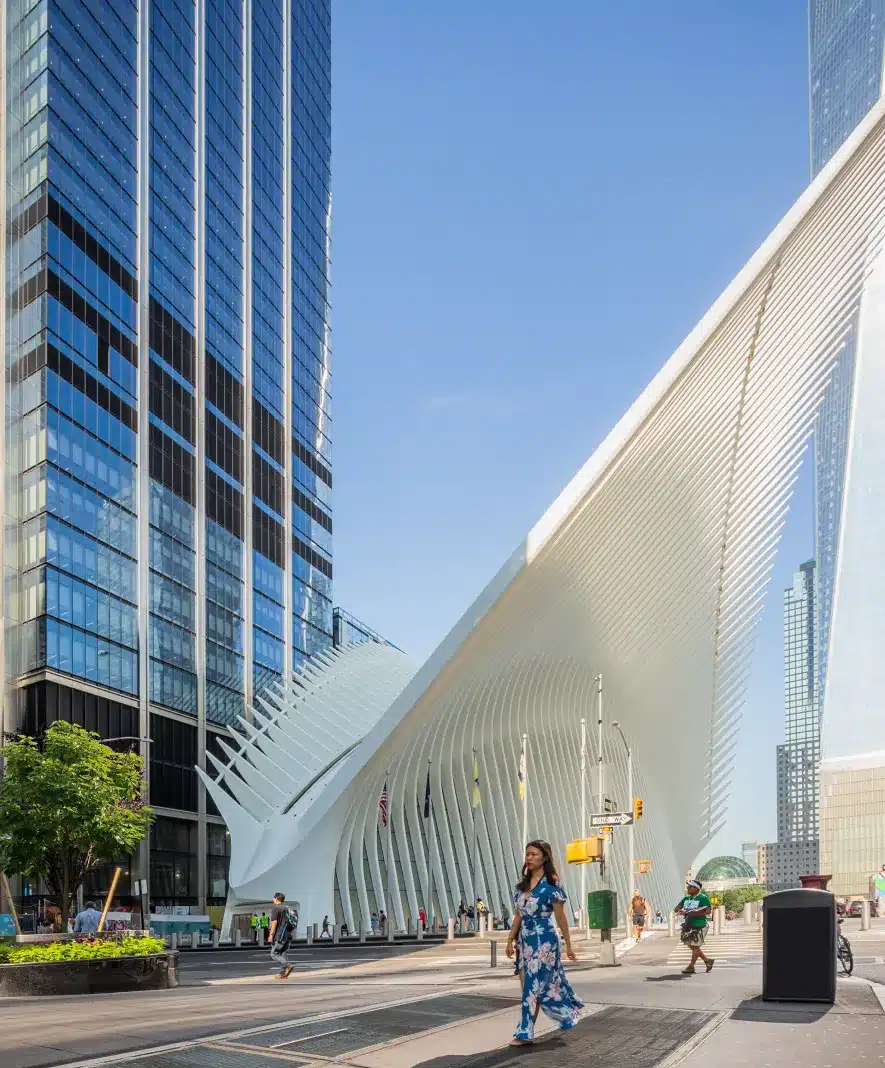 Woman in a floral dress walking past the Oculus, surrounded by modern skyscrapers