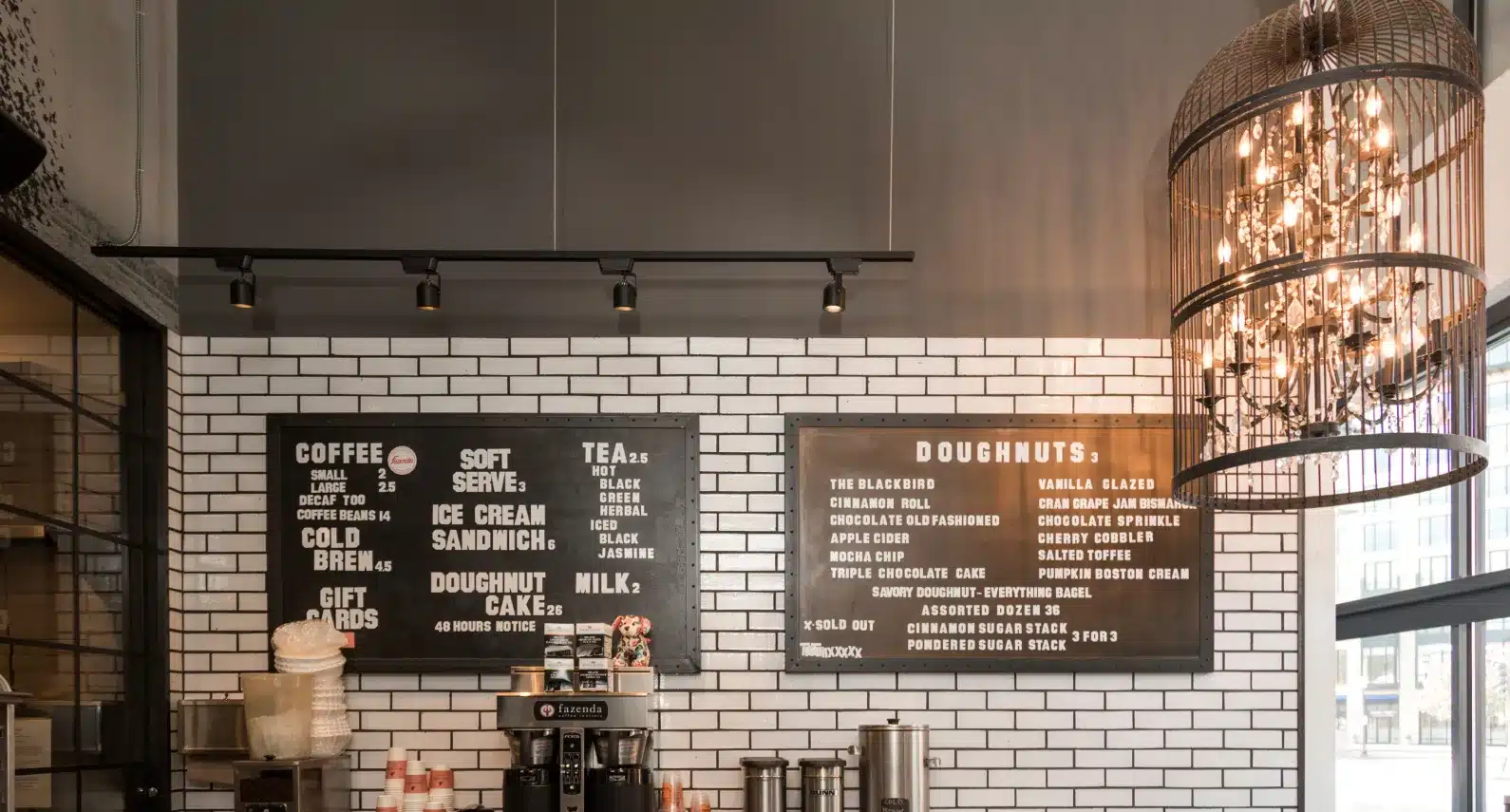 Trendy coffee shop interior with a modern black and white menu and a decorative chandelier