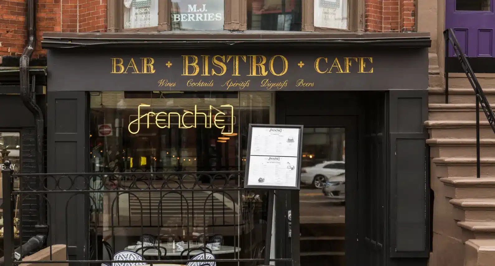 Frenchie bistro entrance with a neon sign, elegant menu display, and Parisian-inspired decor