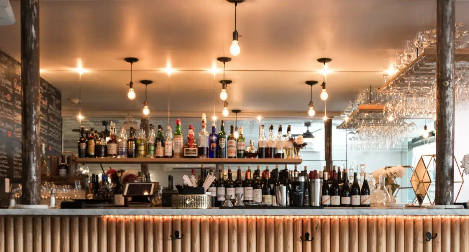 Elegant bar interior featuring warm lighting, an extensive liquor selection, and modern décor