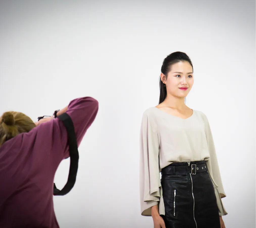 Professional model in a stylish outfit posing for a photographer in a white studio