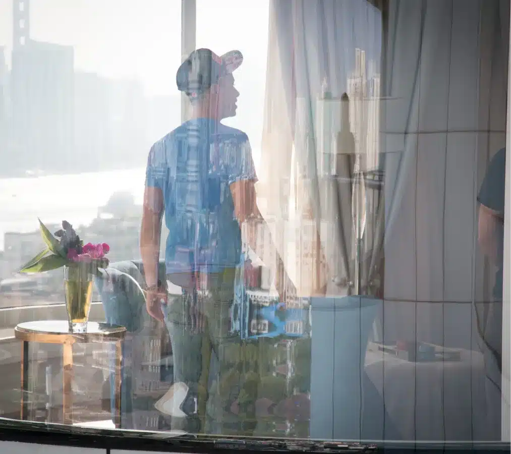 Artistic reflection of a man looking out a window with a city skyline in the background