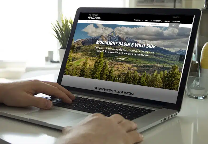 Hands on a keyboard exploring mountain property listings on The Big Sky Real Estate website