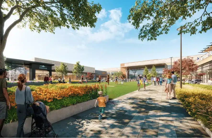 Modern retail plaza with a scenic outdoor park and shoppers strolling under a clear blue sky
