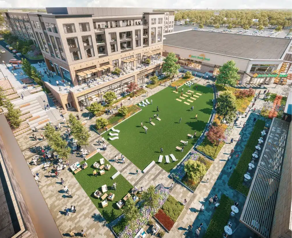 Aerial view of a mixed-use development with a green courtyard, retail shops, and outdoor seating