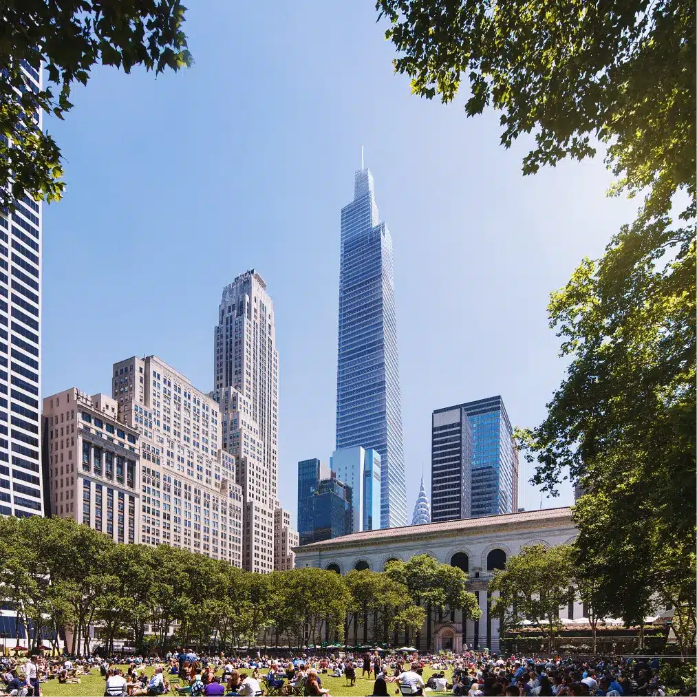 Vibrant city park scene with people relaxing under blue skies, surrounded by modern skyscrapers.