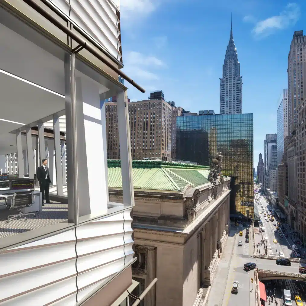 A professional standing on a modern balcony overlooking New York City’s historic landmarks
