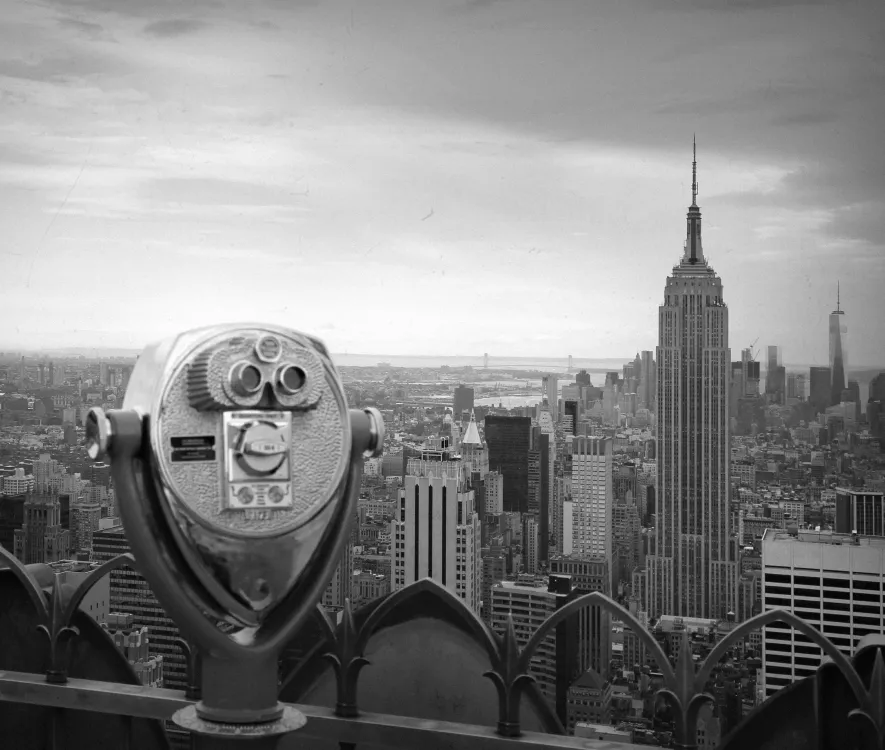 Black and white cityscape view with a vintage coin-operated binocular and the Empire State Building