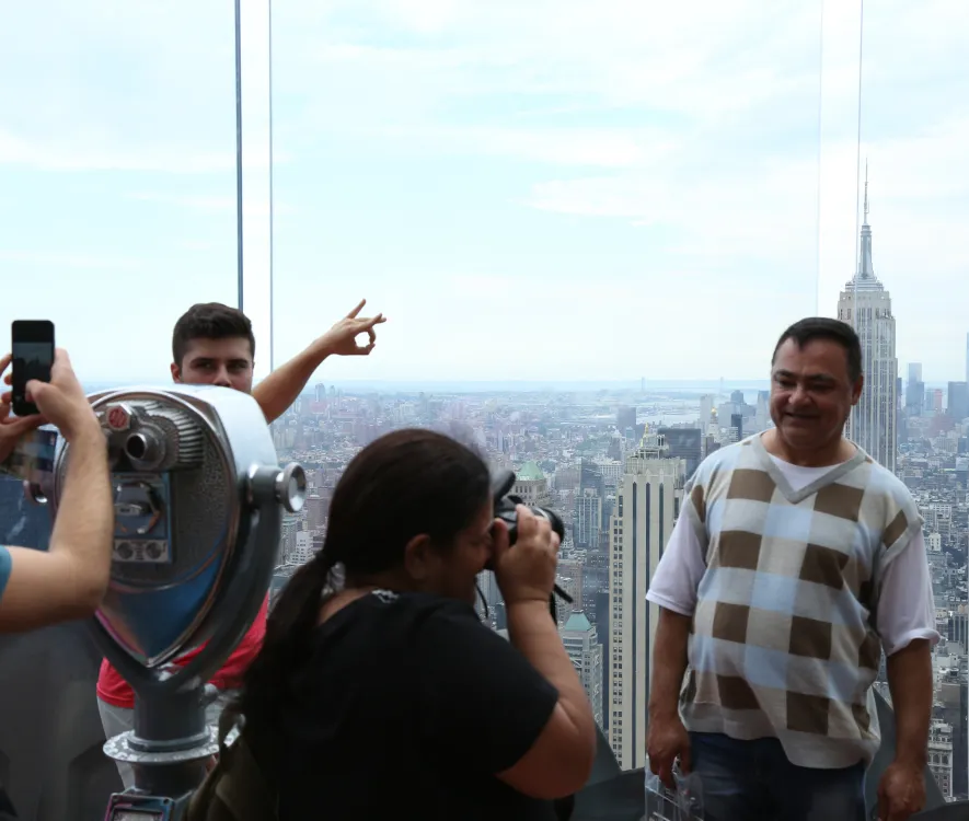 Tourists taking photos from a high-rise observation deck with the Empire State Building behind them