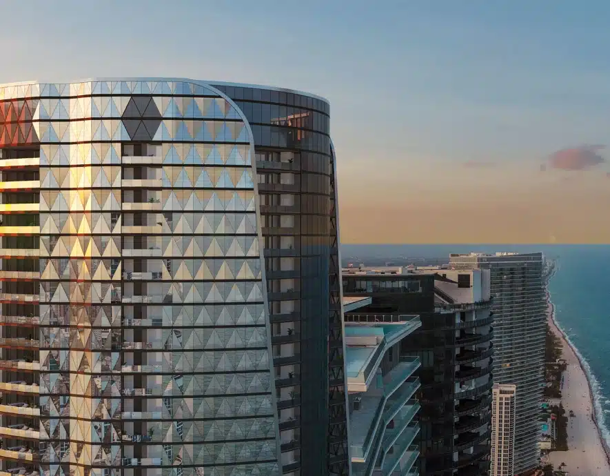 Luxury high-rise with a sleek glass facade reflecting the sunset over the ocean