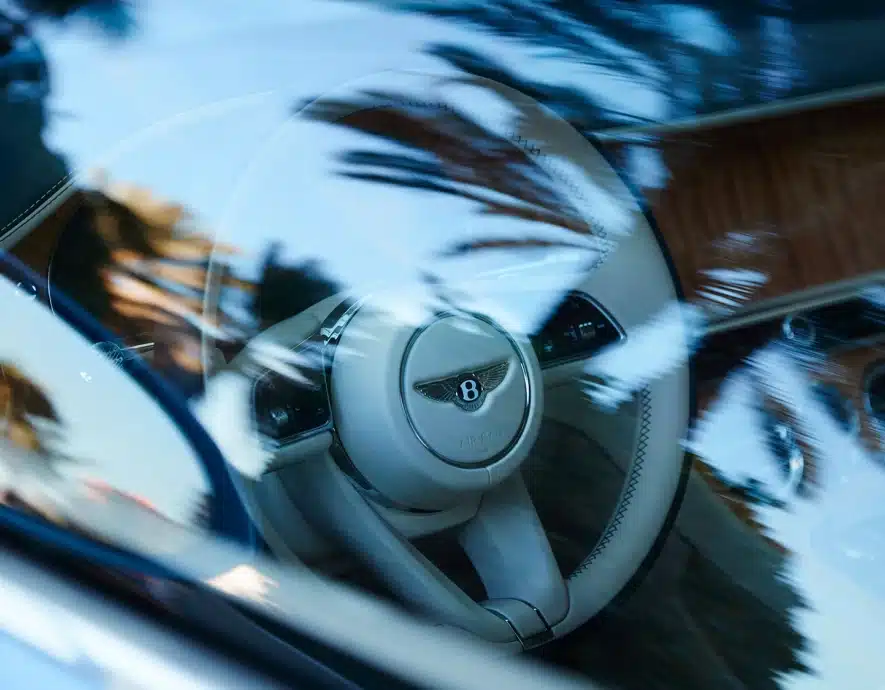 Close-up of a Bentley car’s luxurious leather-wrapped steering wheel with intricate stitching