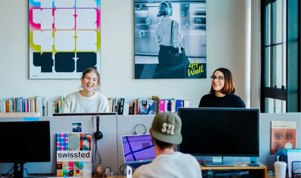 Creative team chatting and laughing together in a modern office filled with colorful art