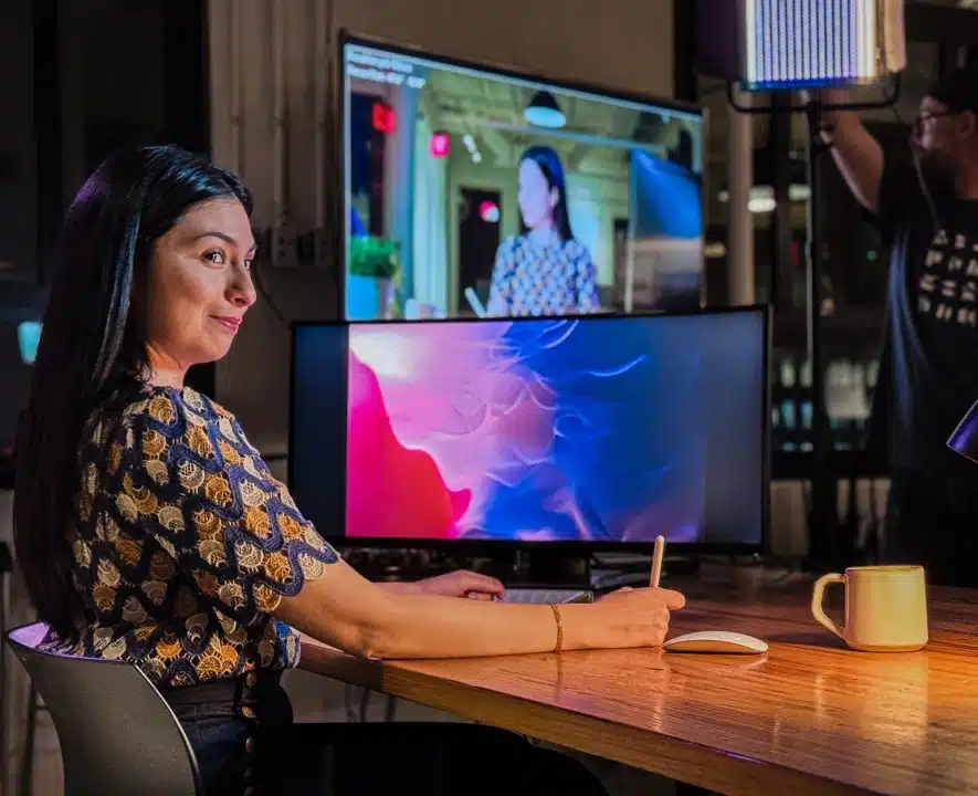 Creative professional using stylus at workstation with large monitor and lighting setup