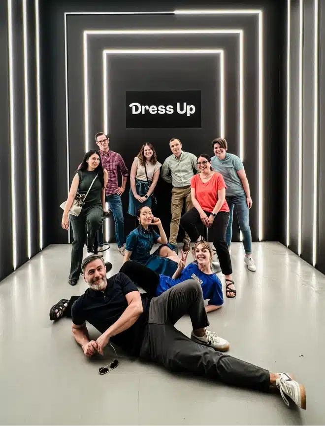 Coworkers celebrate company culture by posing together under artistic light tunnel with branding display