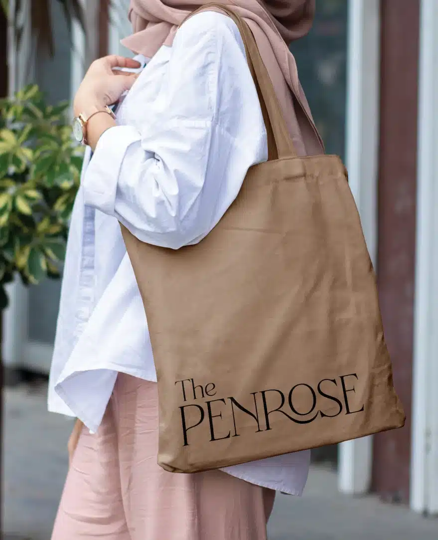 Branded Penrose tote bag held by woman dressed in white blouse and tan hijab