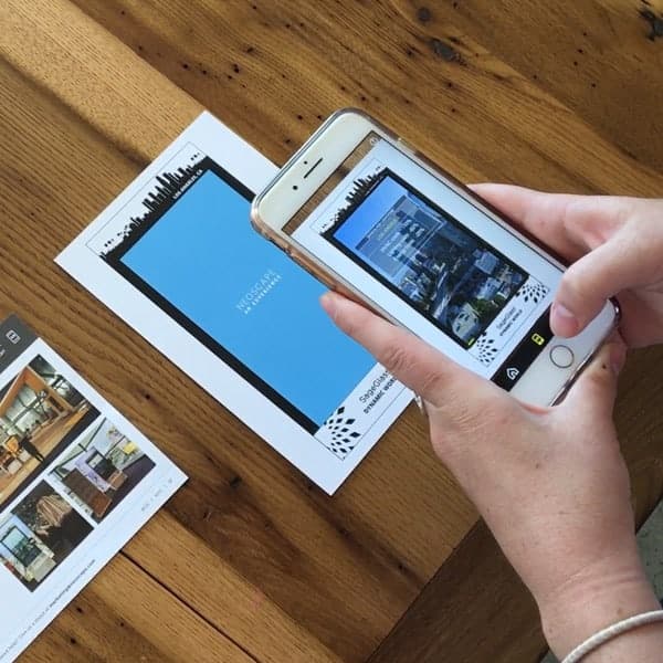 Person using phone camera on real estate brochure to trigger augmented reality experience