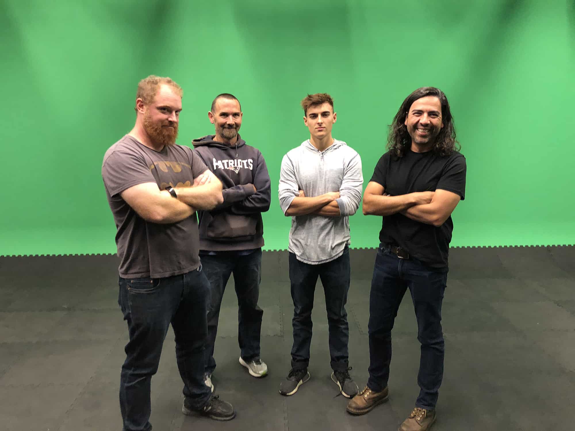 Creative production team casually posing in front of green screen in studio environment
