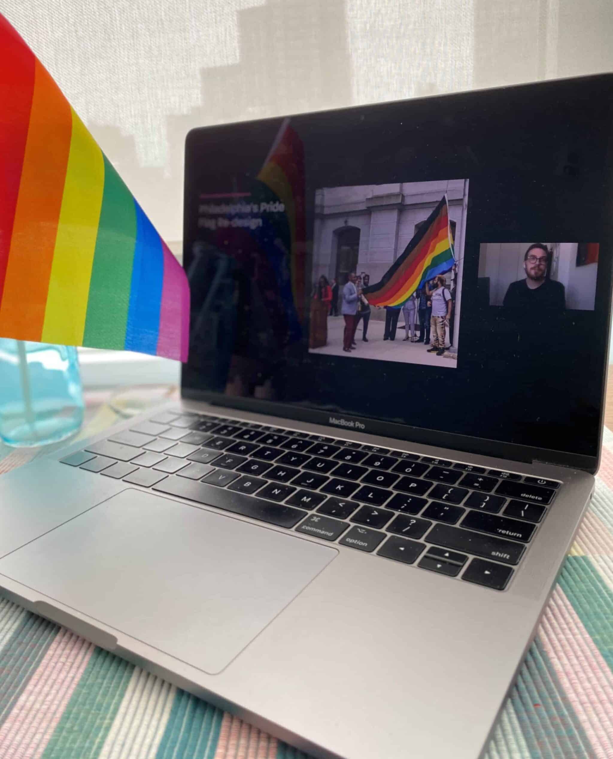 Laptop with Philadelphia Pride flag on screen beside window, emphasizing LGBTQ+ inclusive presentation