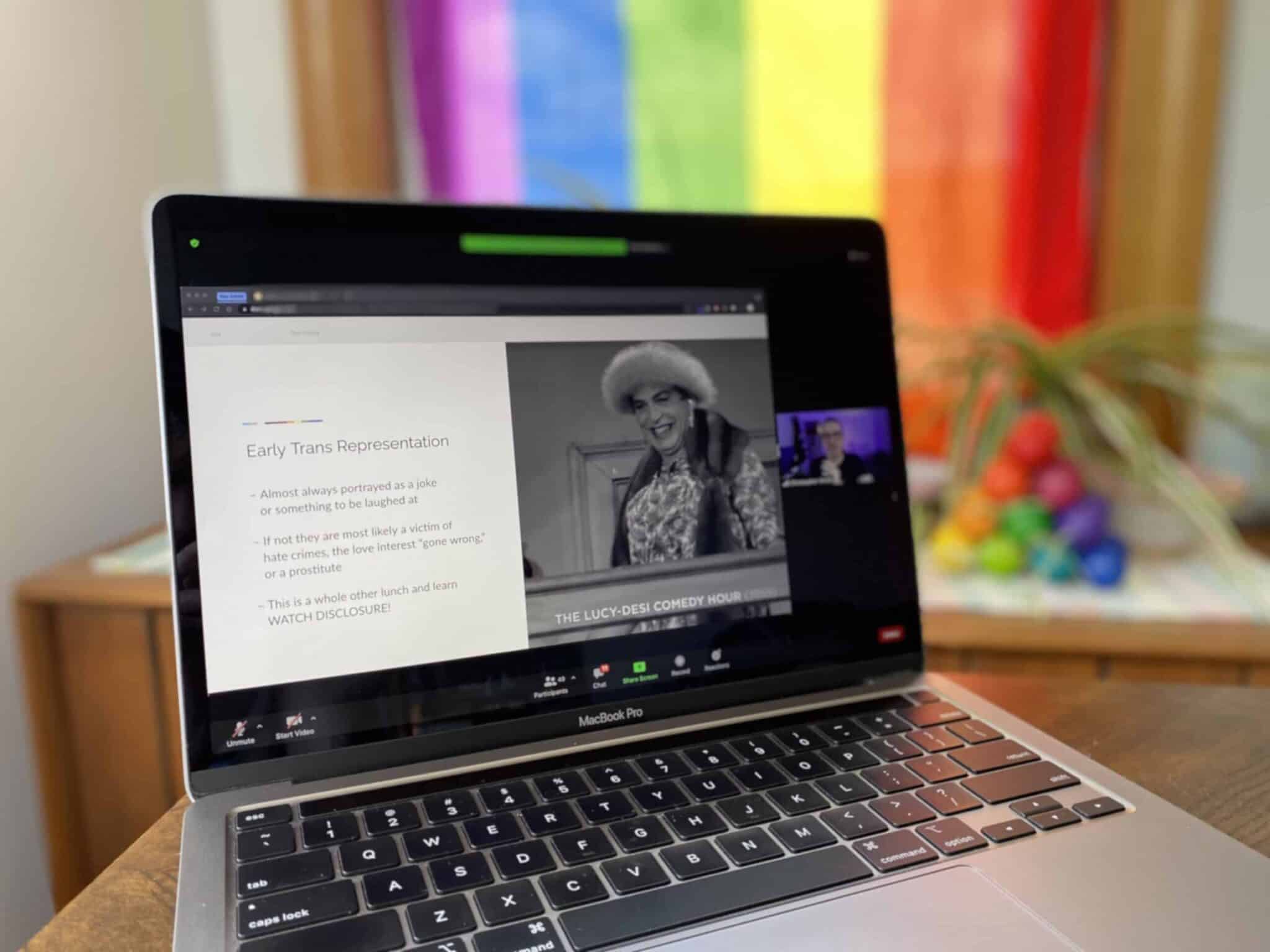 Educational Zoom meeting discussing LGBTQ+ topics held in home office with pride-themed decor