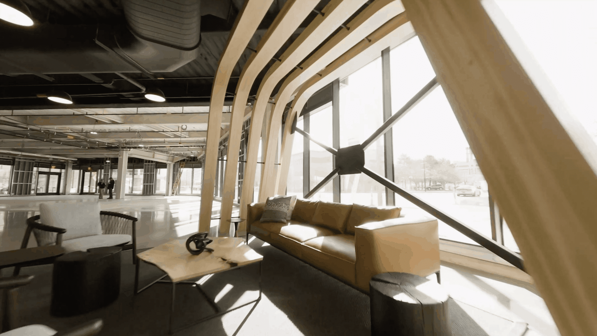 Bright interior lounge with modern furniture, architectural wood structure, and large glass walls