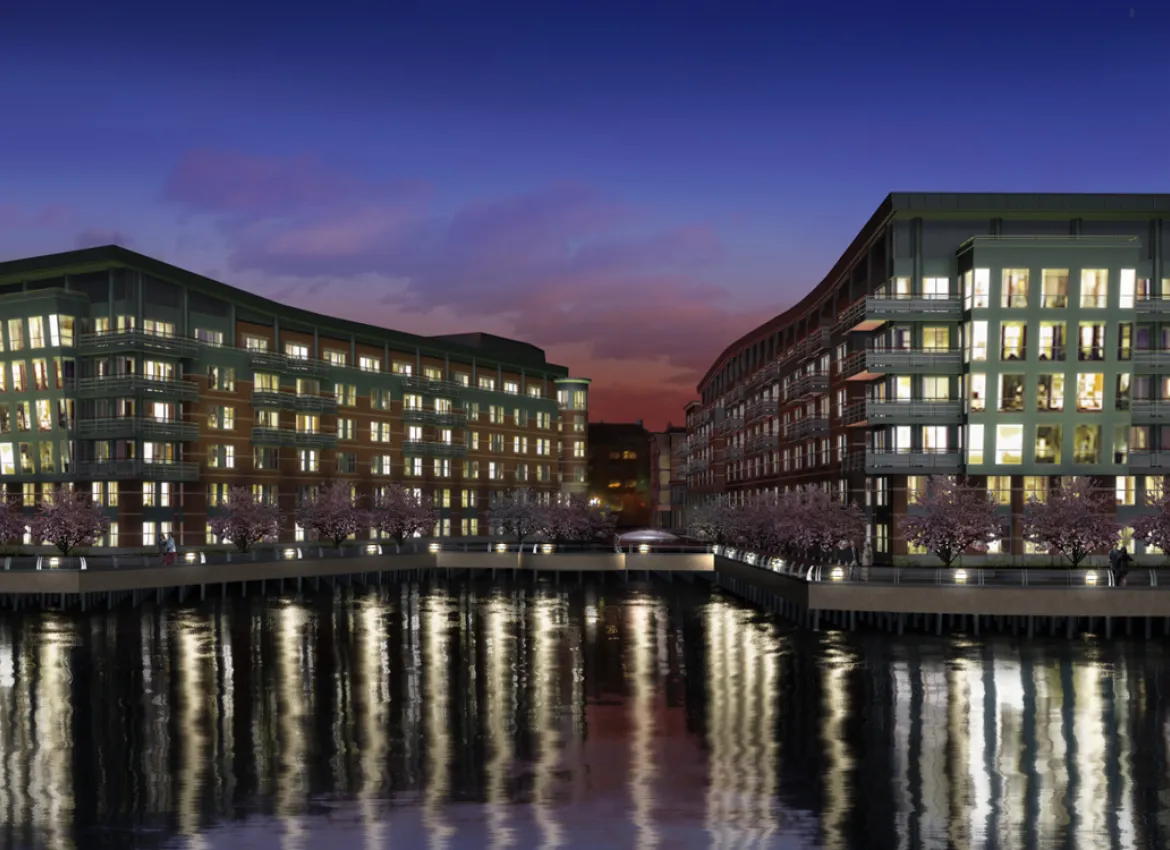 Waterfront residential complex at night reflecting lights across calm water surface