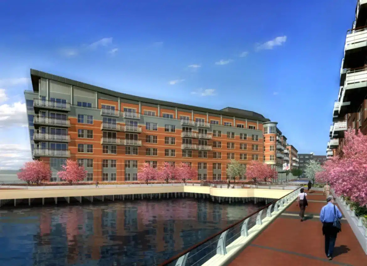 Waterfront apartments with cherry blossom trees lining pedestrian walkway beside water