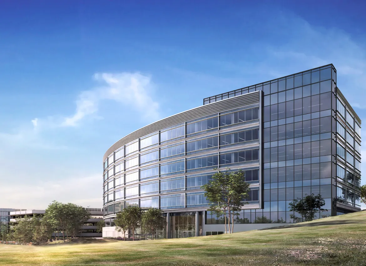 Sleek curved glass office building surrounded by green lawn under clear blue sky in daylight