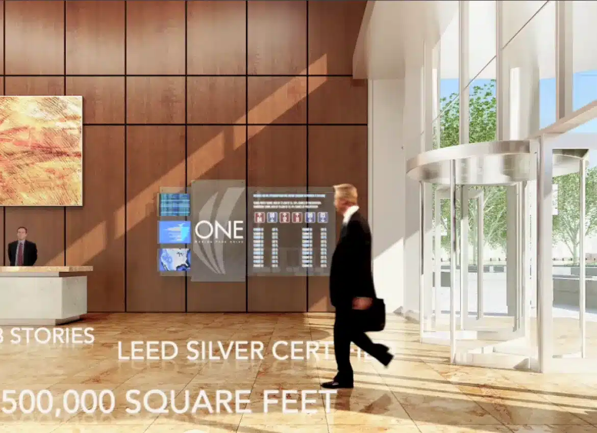 Businessman entering bright office lobby with receptionist desk and illuminated branding wall display