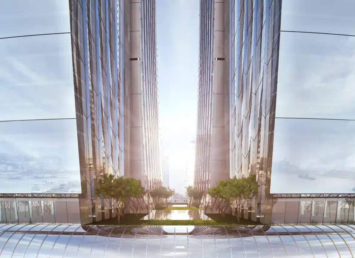 Two tall glass towers connected by elevated garden terraces with sunlight reflecting on facades