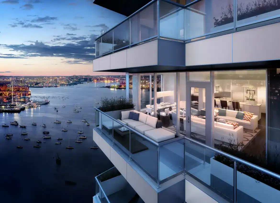 Modern apartment terrace with glass railings overlooking waterfront marina at twilight evening view