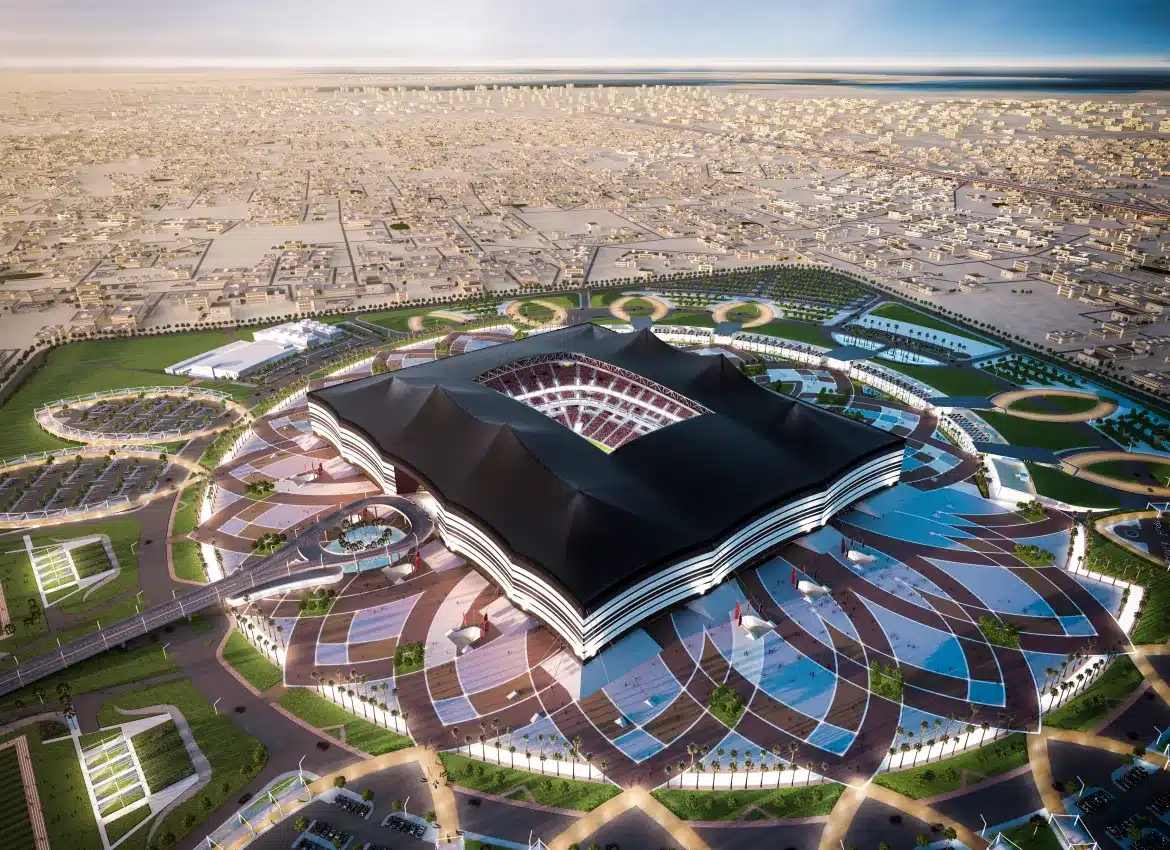 Aerial view of futuristic stadium with petal-shaped design illuminated at dusk in Qatar