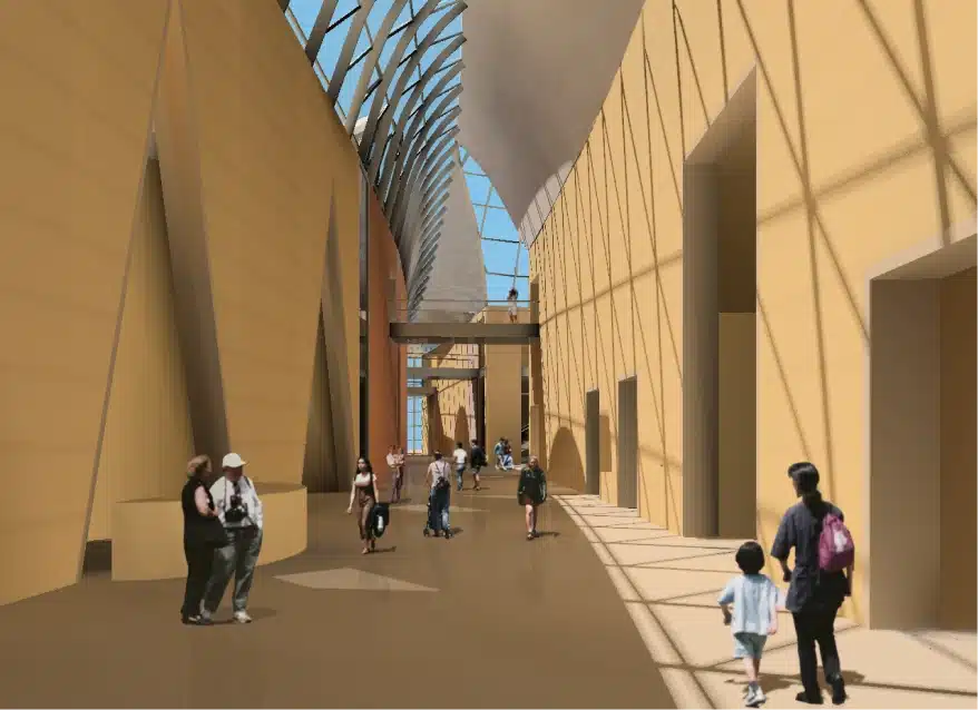 Modern interior hallway with vaulted glass ceiling and people walking along sunlit path