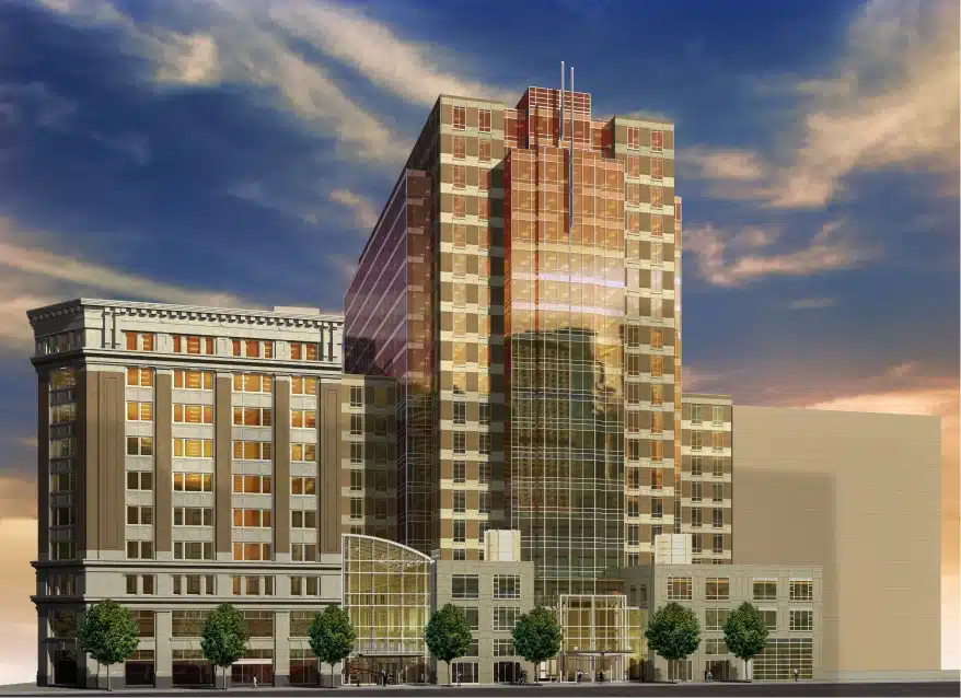 Modern glass high-rise building reflecting evening sky with adjacent historic architecture and street trees