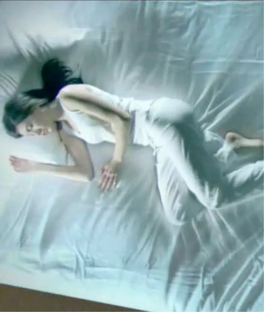 Woman peacefully sleeping on white bed dressed in soft loungewear under gentle ambient light