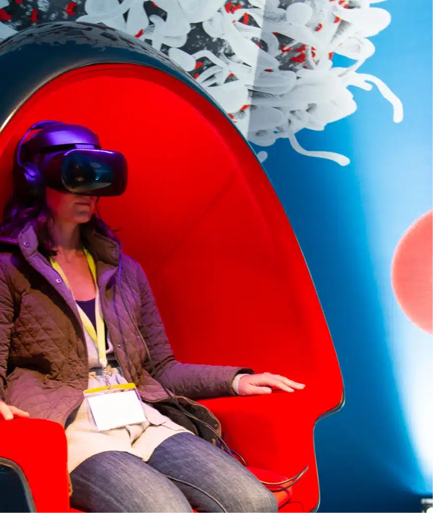 Woman wearing virtual reality headset seated in futuristic red pod immersive technology experience