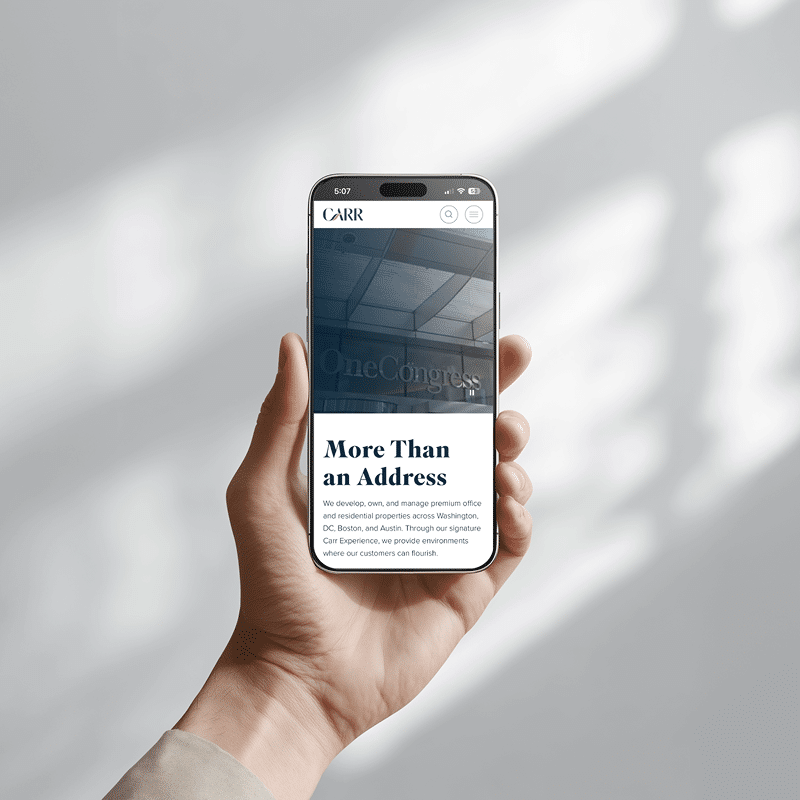 Hand holding smartphone displaying commercial real estate website with responsive mobile design and premium office listings