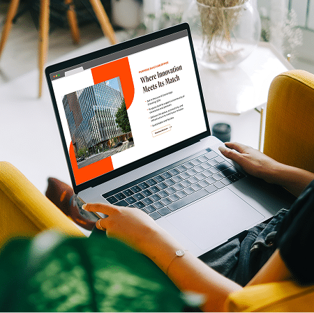 Person browsing commercial real estate website on laptop featuring modern office development and responsive design