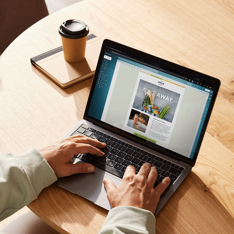 Digital marketer designing branded email campaign with laptop and coffee during work session