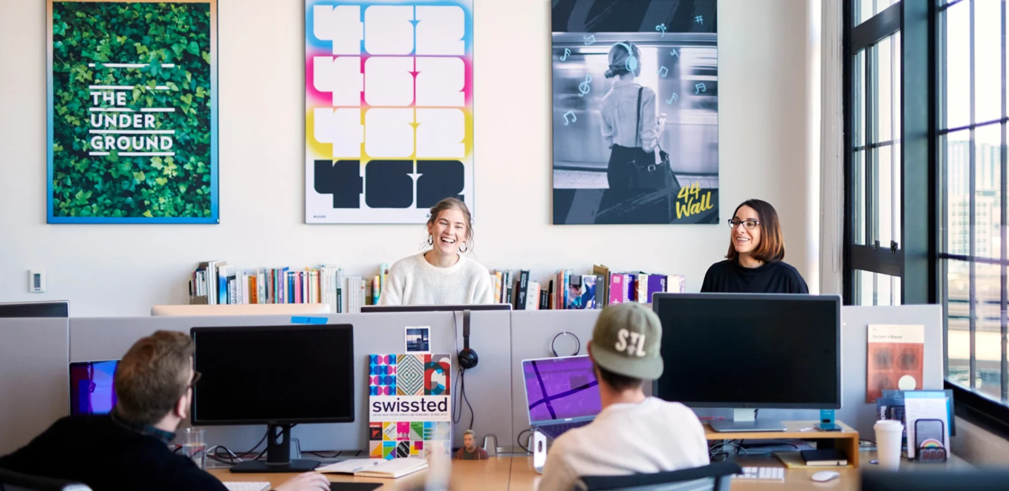 Creative agency team collaborating in modern office with colorful design posters and collaborative workspace atmosphere